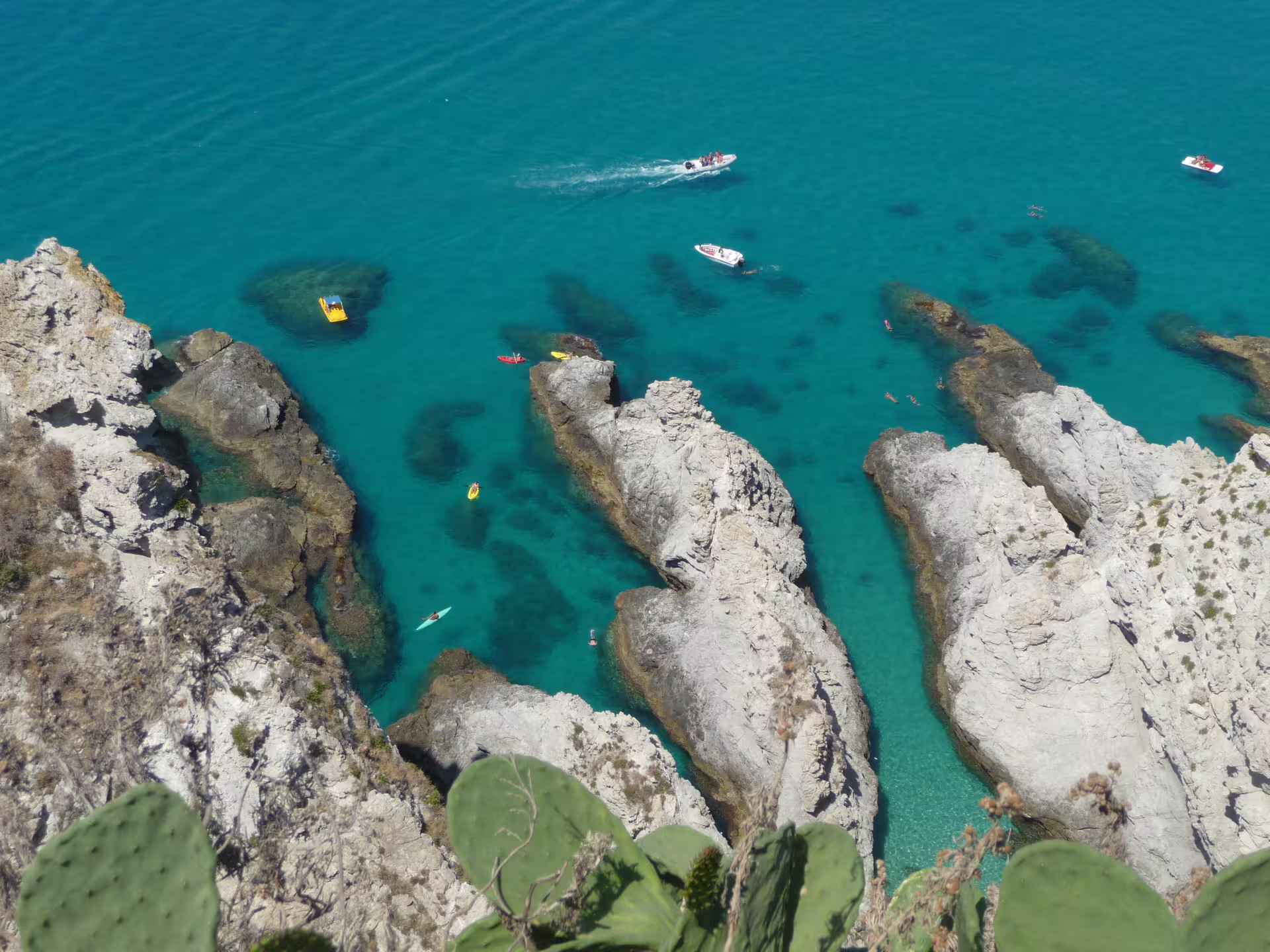 Kayaks and boats explore turquoise Tyrrhenian Sea coves and rocky cliffs near Cosenza on a 5-day Calabria coastal tour