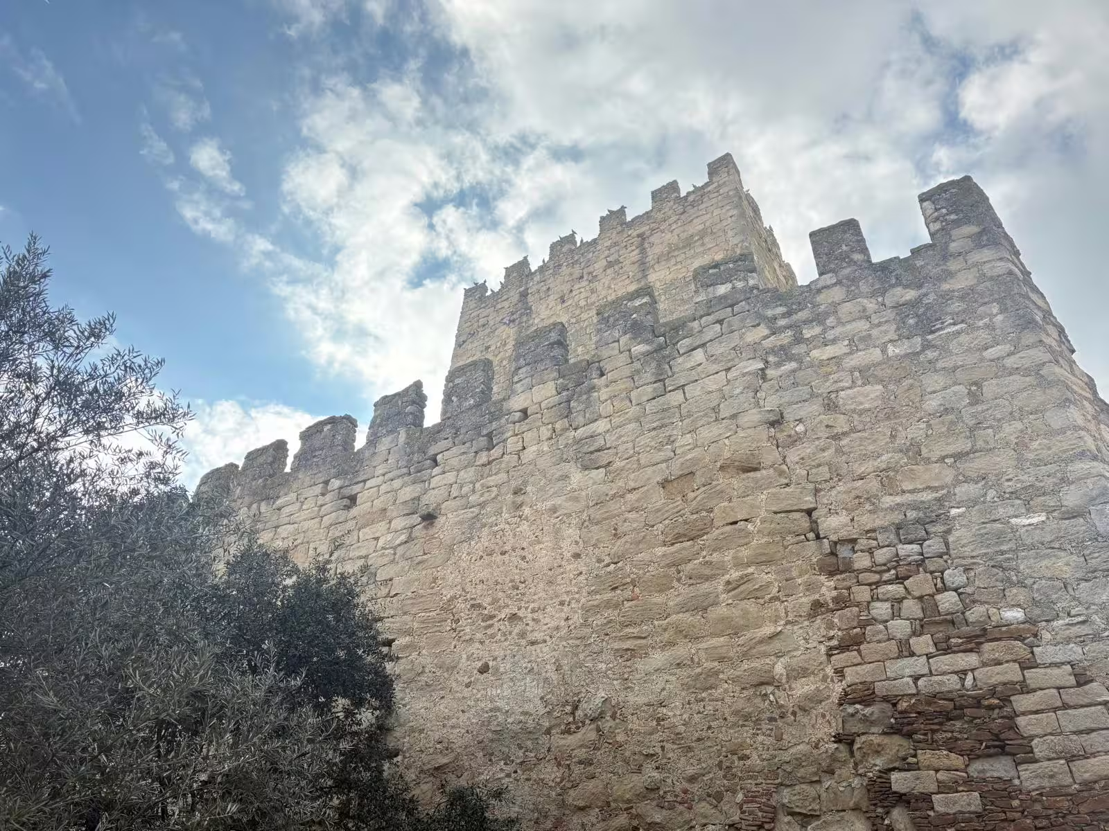 Historic stone castle with crenellated walls set against a bright blue sky in Costa Brava.