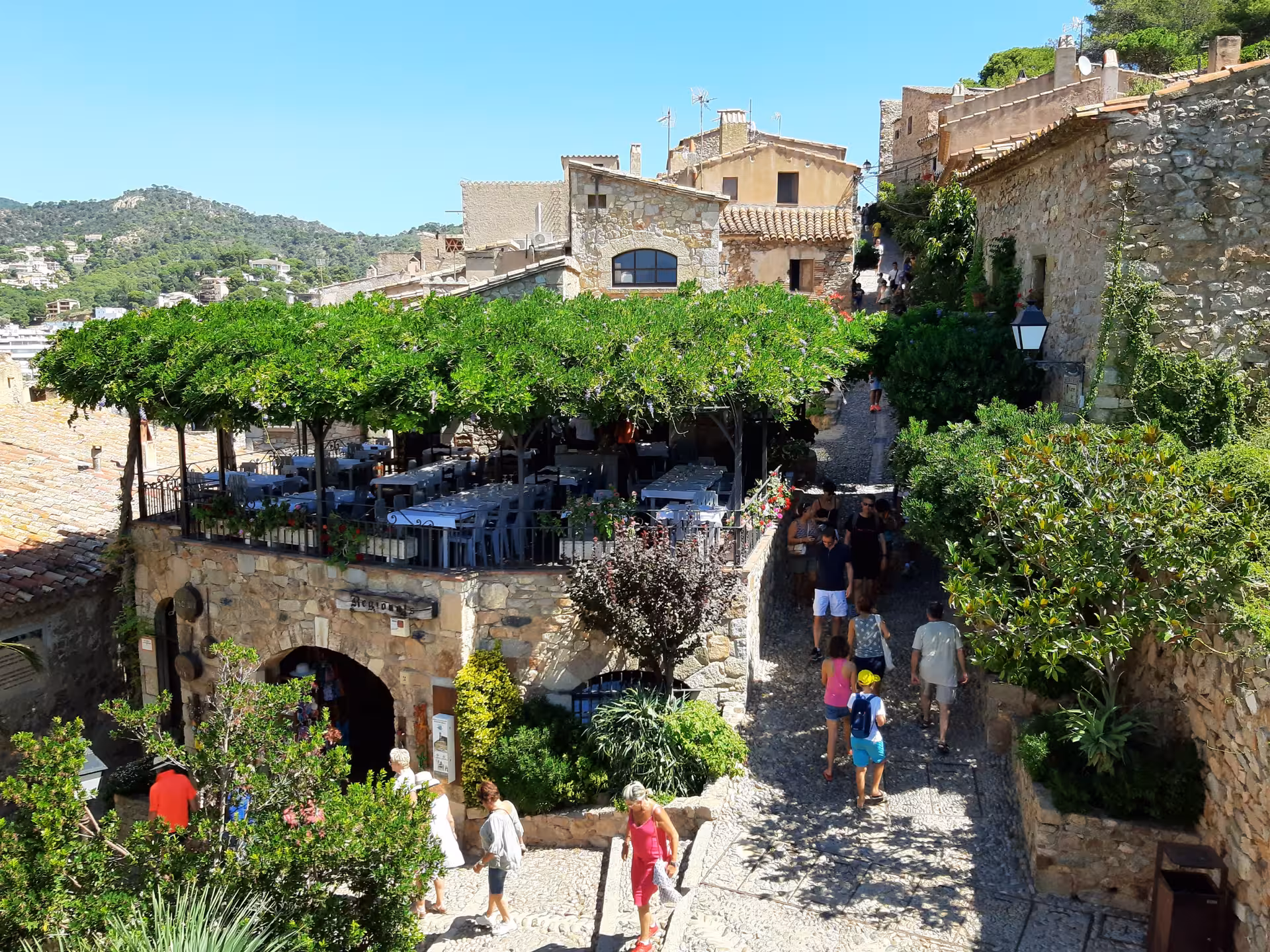 Medieval Costa Brava village street with stone houses and terrace café, scenic day trip from Barcelona