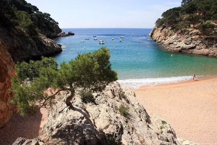 Secluded beach cove in Costa Brava with turquoise waters and rocky cliffs, perfect for Girona City excursions.