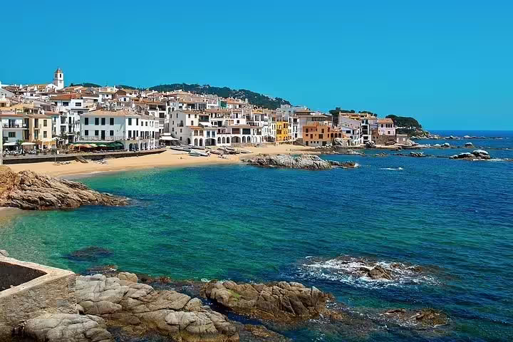 Picturesque coastal town in Costa Brava with colorful buildings and sandy beach, featured in Dalí Museum tour.