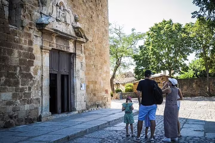 Family exploring historic stone architecture on a sunny Costa Brava tour, highlighting cultural heritage and history.