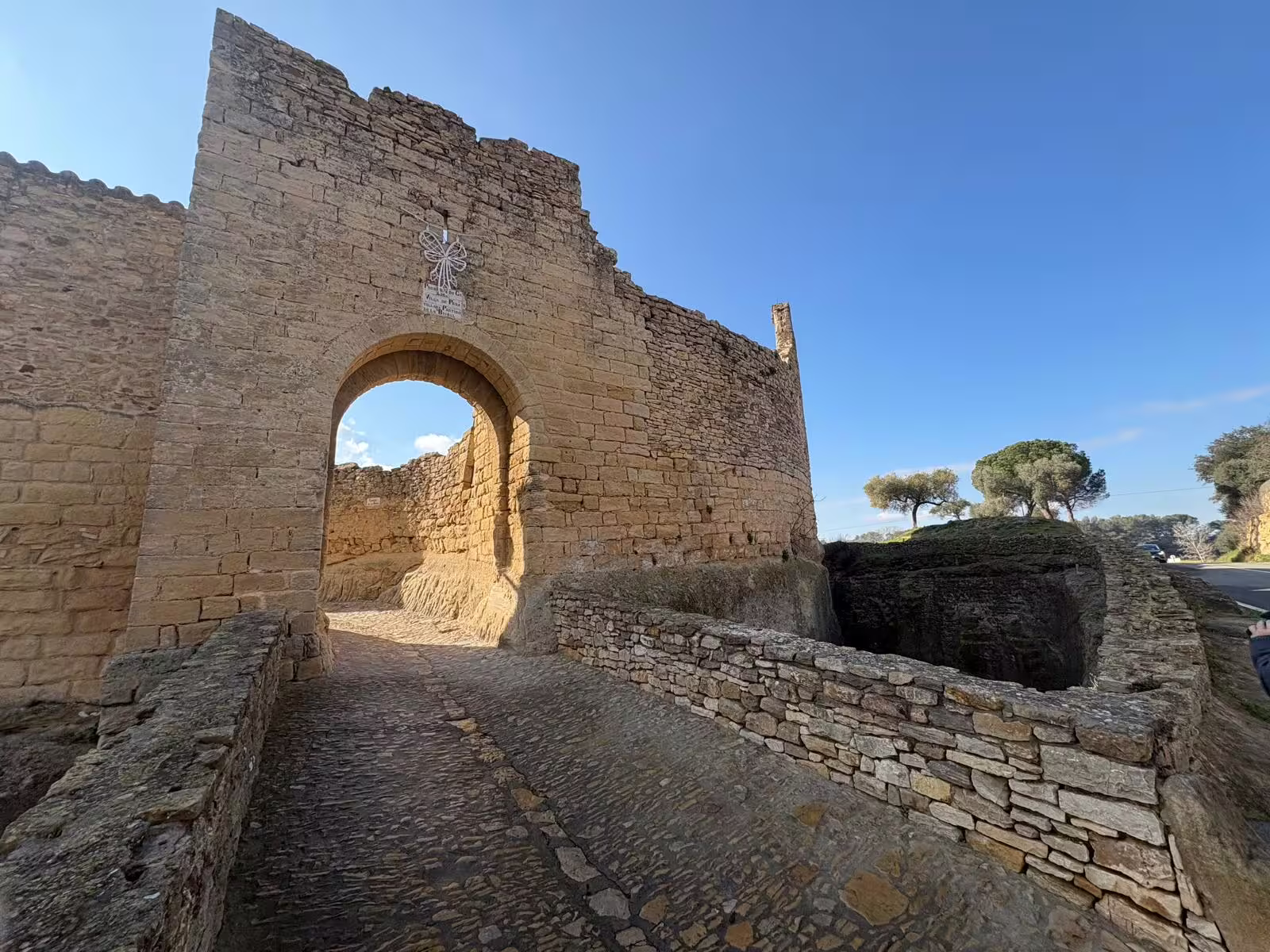 Historic stone archway in a Costa Brava village, showcasing ancient architecture and scenic landscape views.