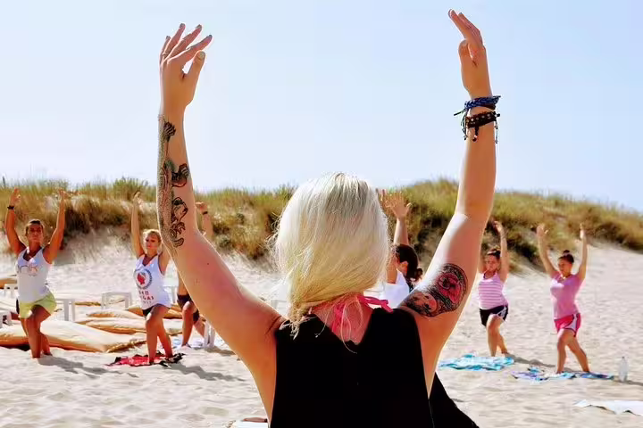 Participants enjoy a beach yoga session under the sun at Costa da Caparica, blending wellness and scenic beauty near Lisbon.