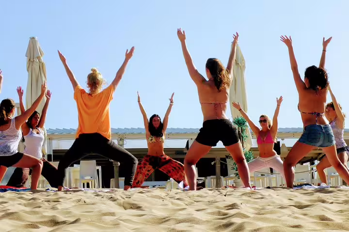 Group practicing yoga on the sandy beach at Costa da Caparica, perfect for a rejuvenating surf and yoga retreat from Lisbon.
