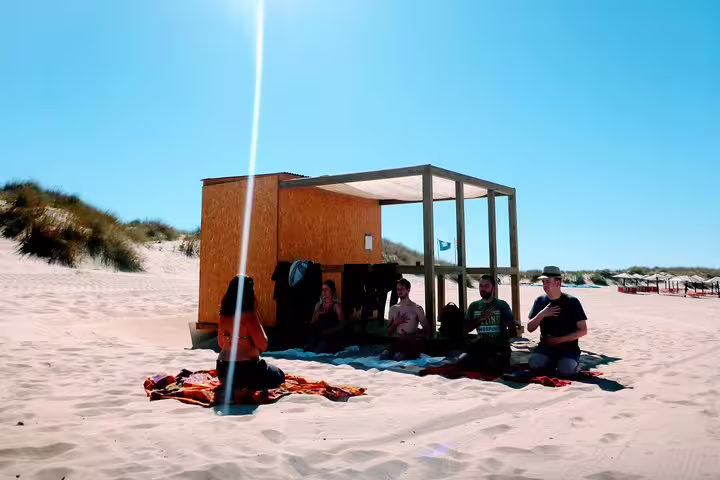 Group enjoying a yoga session on sunny Costa da Caparica beach, part of a surf and yoga experience from Lisbon.