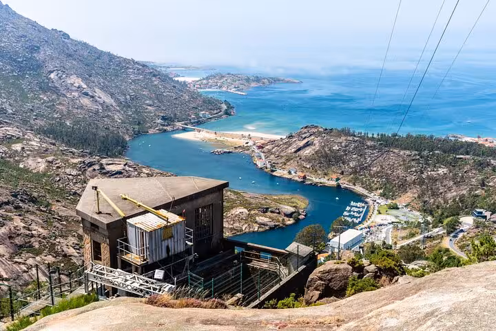 Panoramic view of Costa da Morte's rugged coastline and clear blue waters from a hillside vantage point.