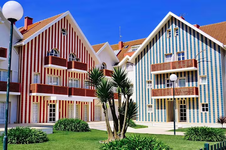 Colorful striped houses in Costa Nova, Aveiro, showcasing traditional Portuguese architecture under a clear blue sky.