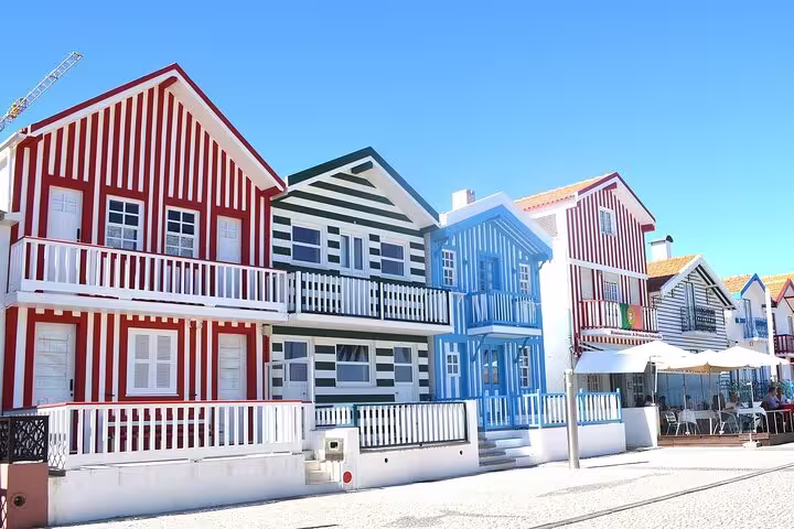 Vibrant striped houses in Costa Nova, a picturesque stopover on the Lisbon to Porto private transfer route.