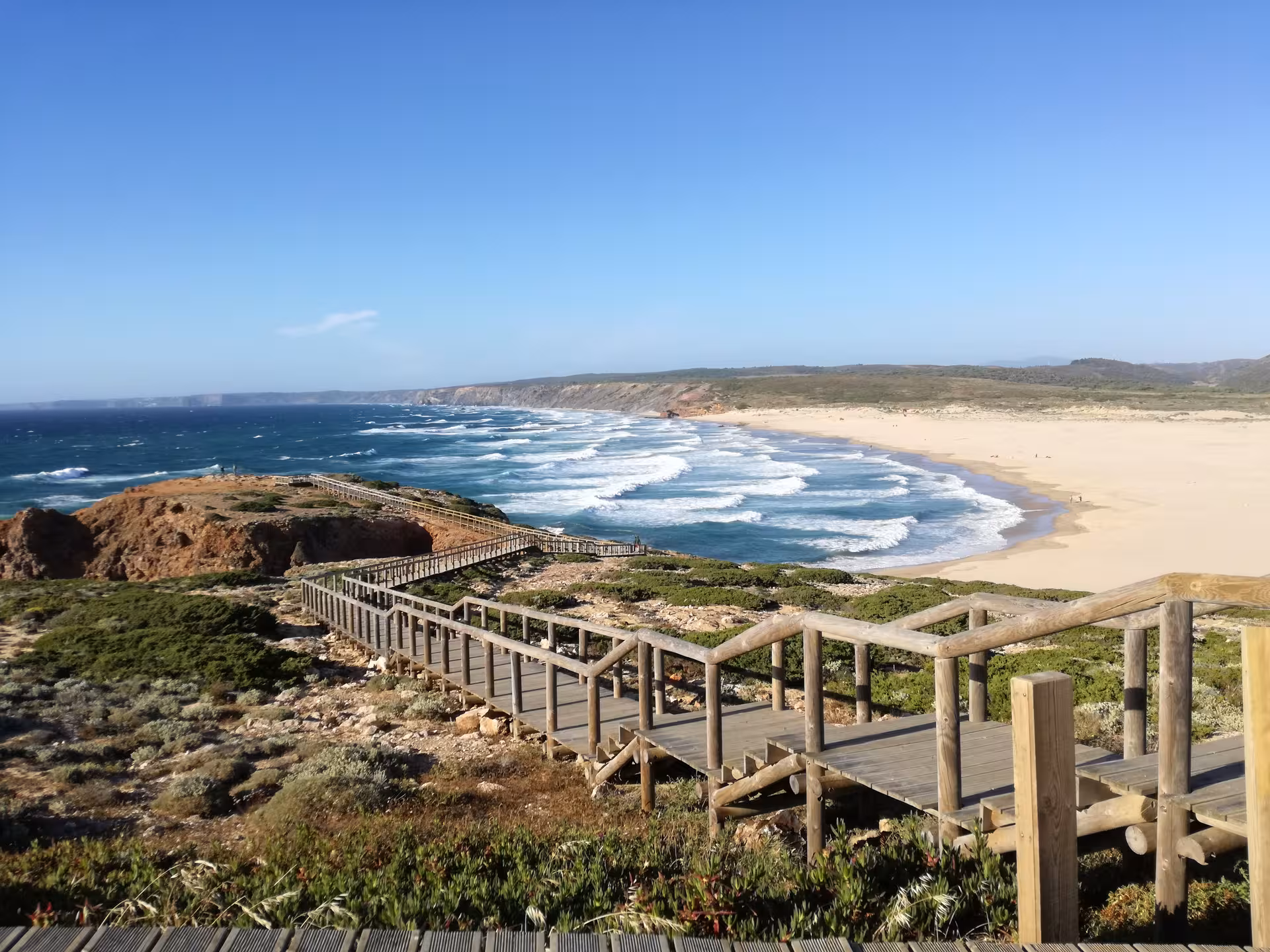 Wooden boardwalk leading to a wild sandy beach and Atlantic waves on Portugal’s Costa Vicentina hiking coastline