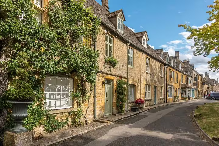 Honey-stone cottages on a quiet Cotswolds village street, a classic day trip from London countryside tour