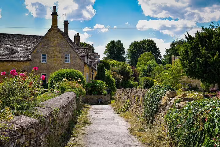 Country lane with stone walls and cottage gardens in the Cotswolds, picturesque day trip from London