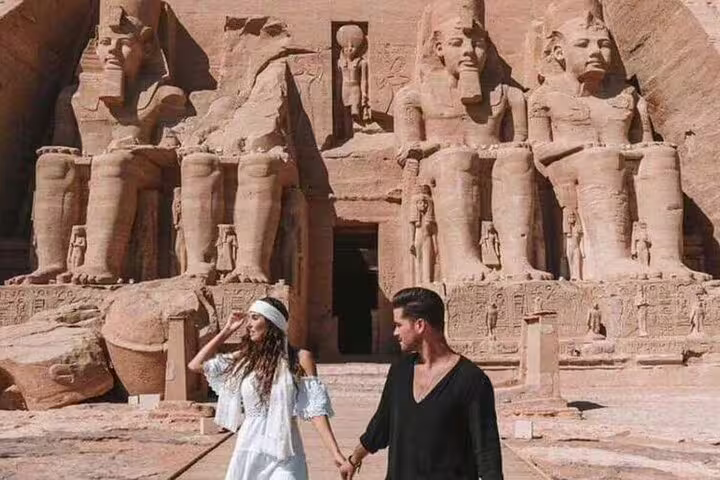 Couple holding hands at Abu Simbel temples in Egypt on Luxor to Aswan tour, iconic Ramses II statues