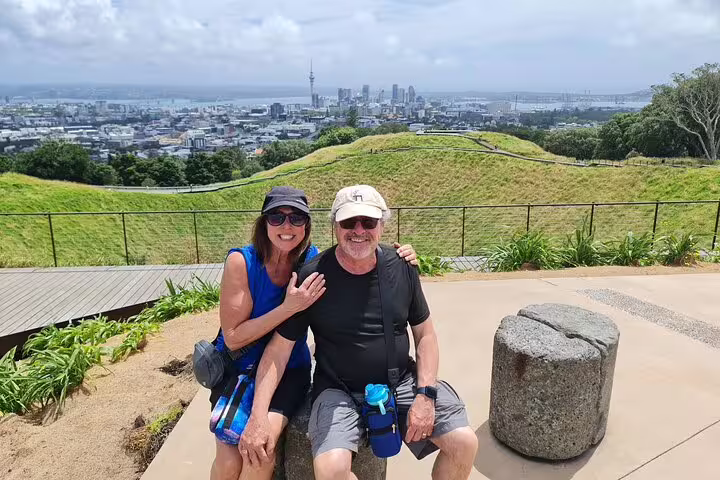 Couple smiles with Auckland's skyline as a backdrop, capturing a memorable moment on a private highlight day tour.