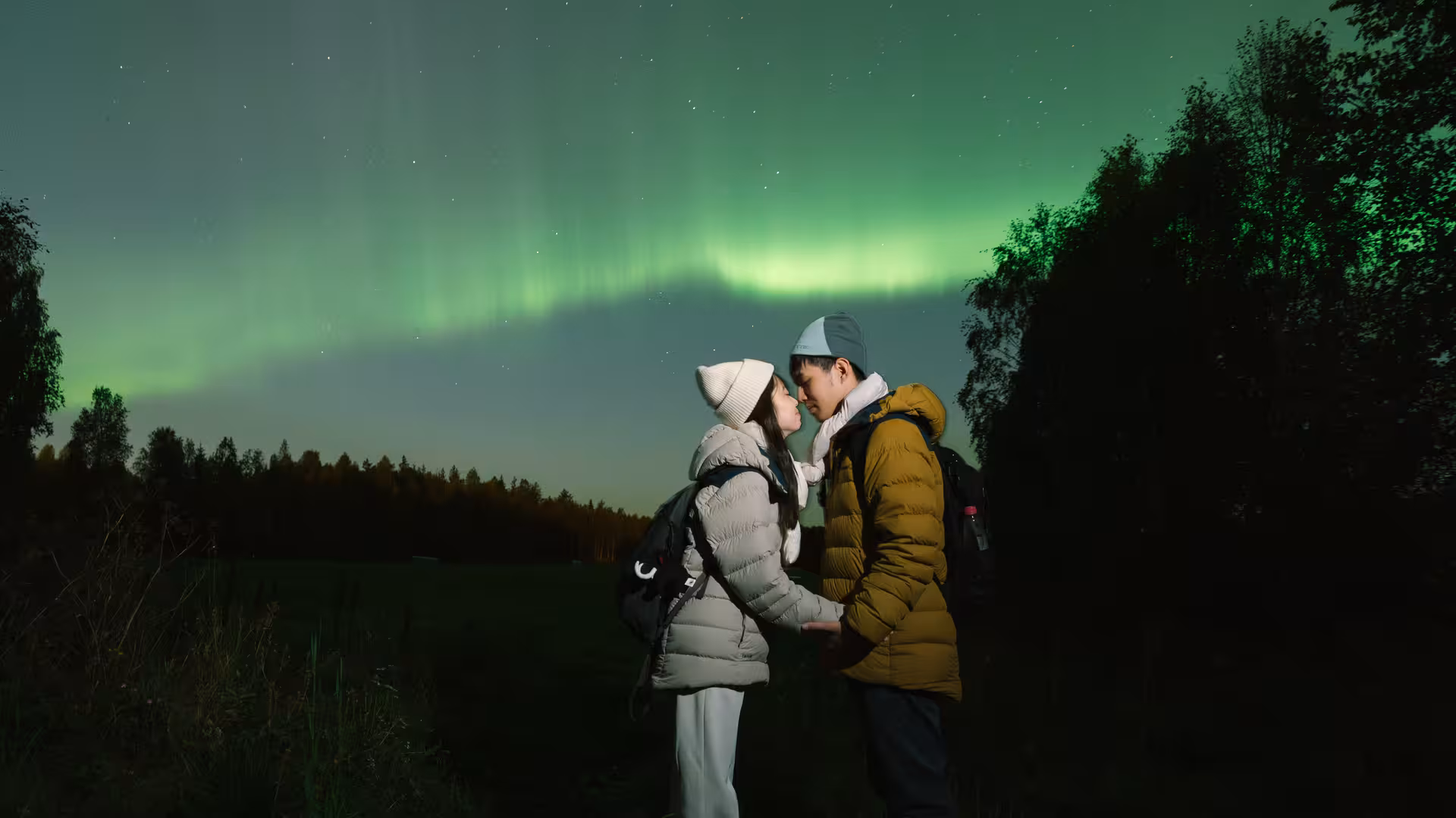 Couple embracing under the mesmerizing green aurora lights during an exclusive photography tour.