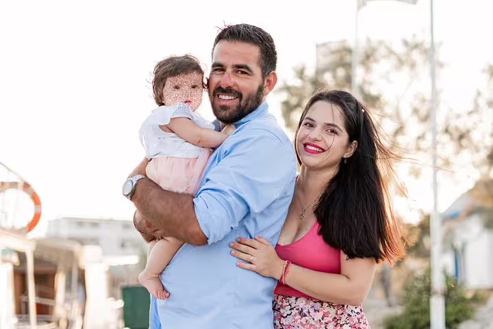 Smiling couple holding their baby during a private photoshoot in the scenic outdoors of Rhodes.