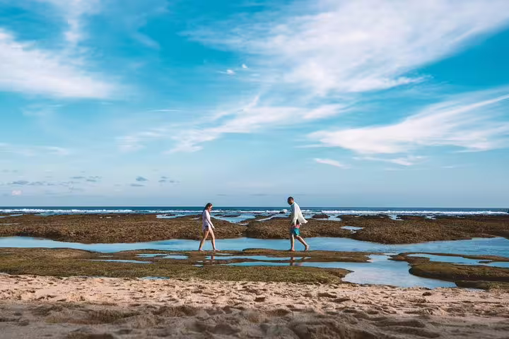 Couple walking on Bali beach at low tide during private vacation photographer photo shoot with ocean backdrop