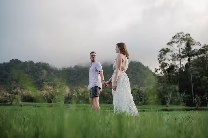 Couple holding hands in Bali rice field at sunset, private vacation photographer capturing romantic portraits