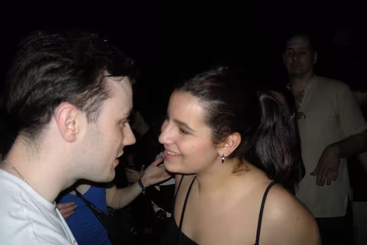 Couple smiling and engaging intimately at a bustling Barcelona club, highlighting the city's vibrant nightlife scene.