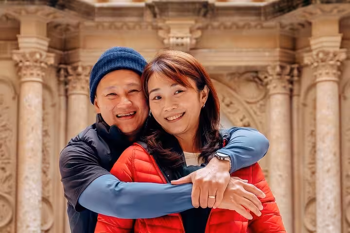 Couple embraces during a private Barcelona photoshoot against ornate historic architecture, capturing romantic, timeless travel portraits.