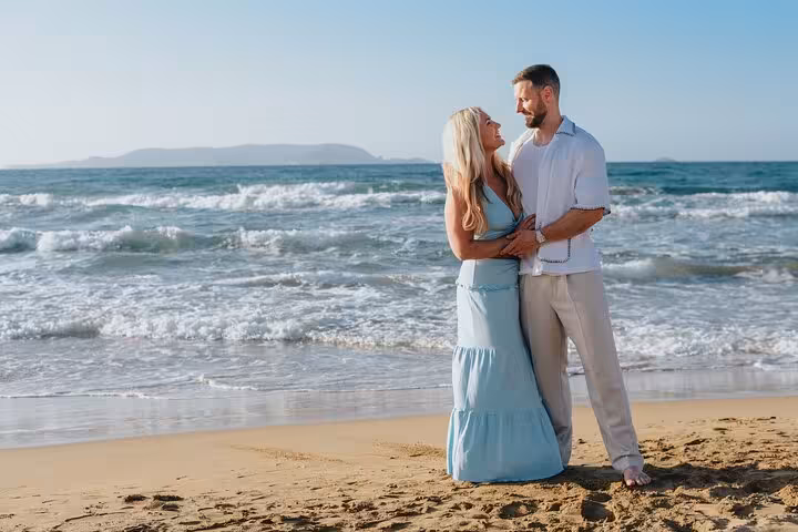 Couple embracing on a sandy beach with waves in the background during a Heraklion photoshoot.
