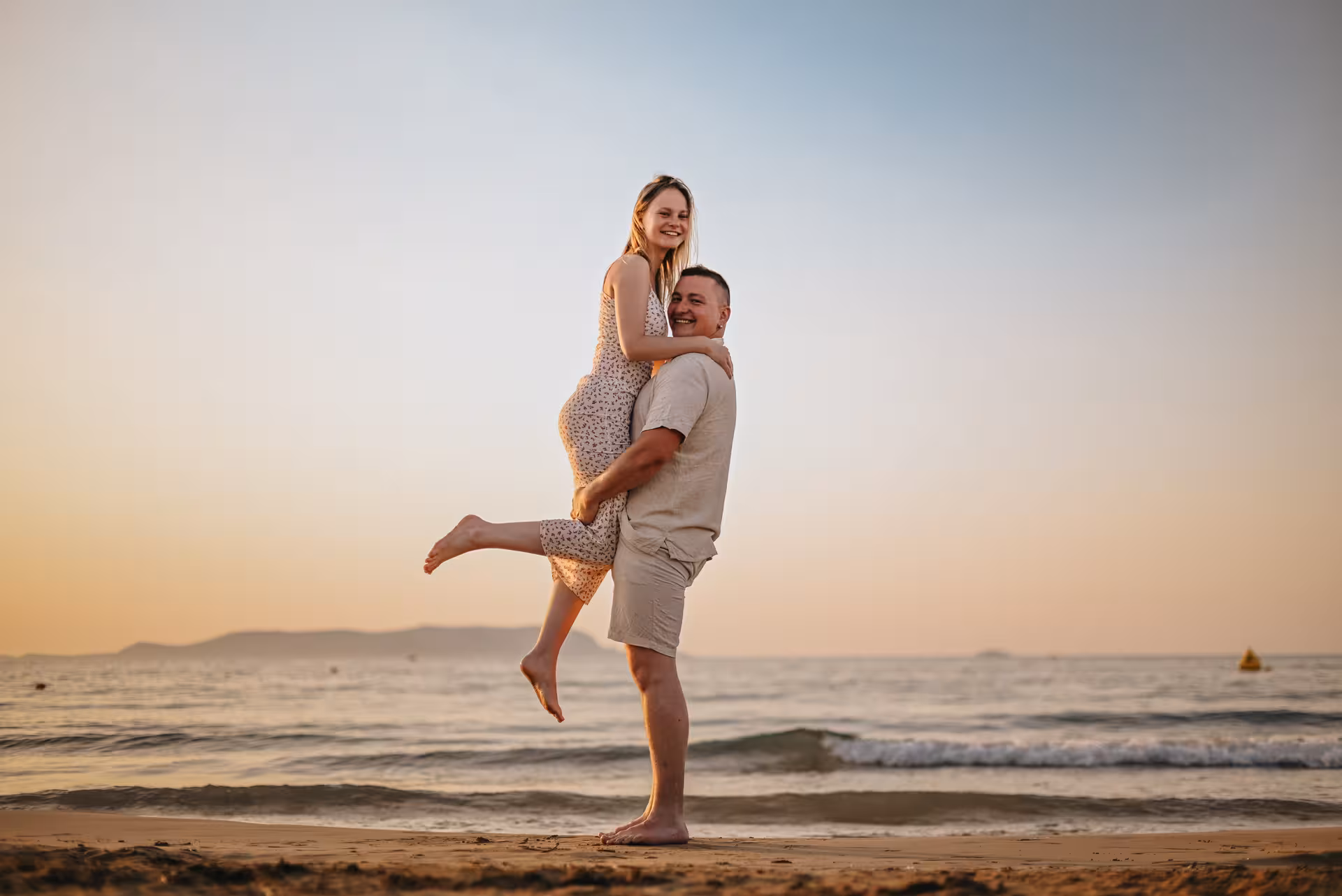 Smiling couple enjoying a playful moment on the beach at sunrise in Analipsi.