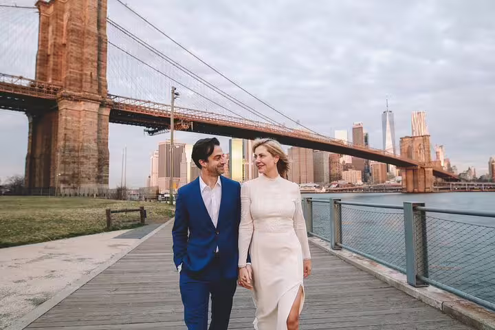 Couple strolling Brooklyn Bridge Park waterfront with Brooklyn Bridge and skyline on a DUMBO photo tour NYC