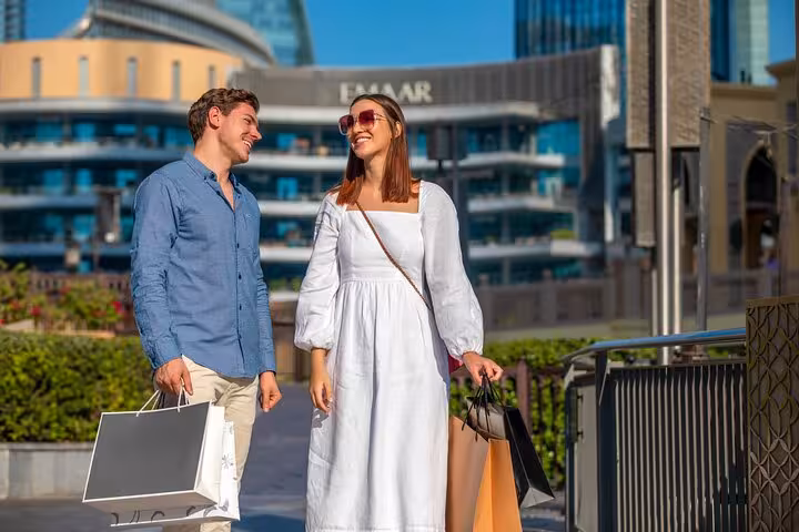 Smiling couple with shopping bags at Emaar Square, capturing memories on the Burj Khalifa Instagram tour.