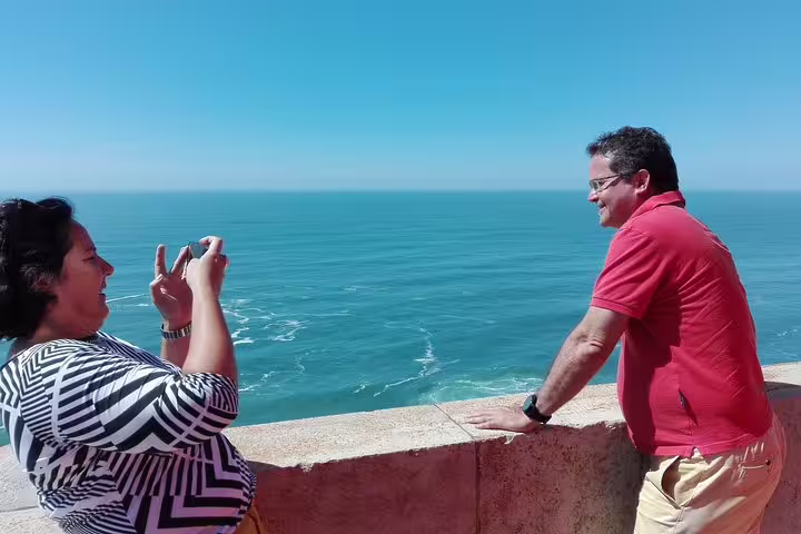 Couple enjoying ocean views at Cabo da Roca during Sintra, Roca, and Cascais full-day private tour with Pena tickets.