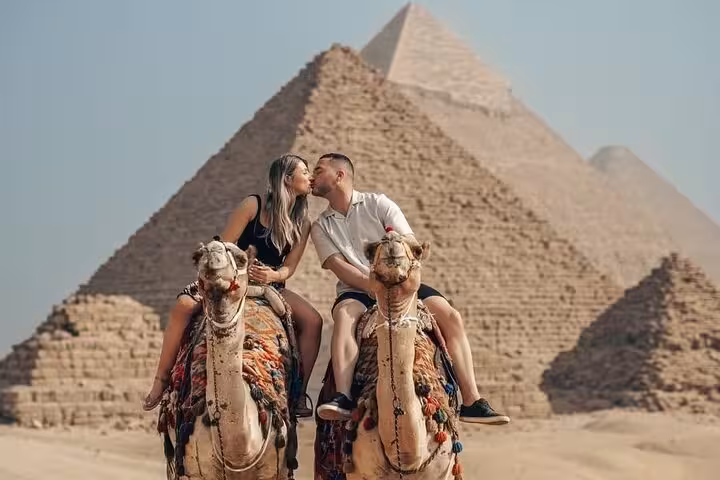Couple riding camels in front of the Great Pyramid of Giza on a full-day Giza Sakkara Memphis tour