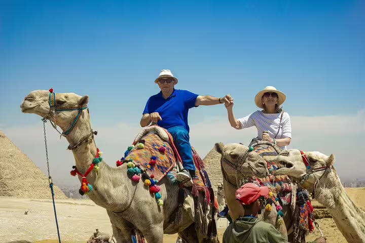 Couple riding decorated camels by the Giza Pyramids, a classic experience on a 3-day Cairo highlights tour