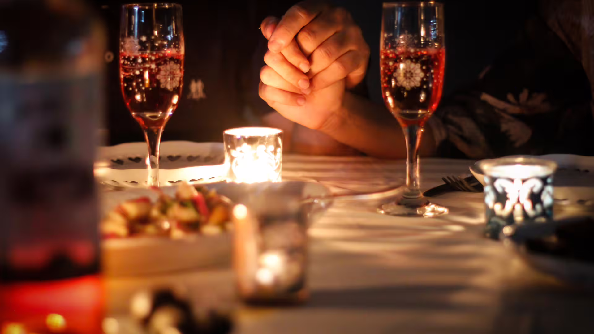 Couple holding hands over candlelit dinner with sparkling wine, perfect romantic evening experience in Solofra