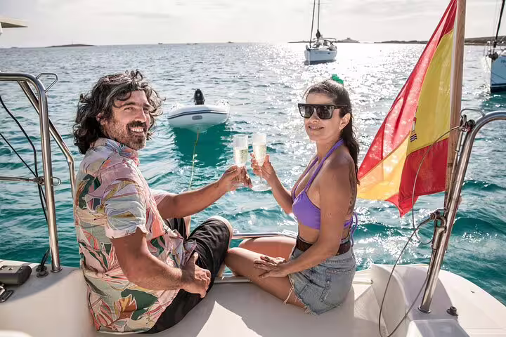 Couple enjoying champagne on a catamaran during a Formentera and Ibiza small group tour, surrounded by turquoise waters.