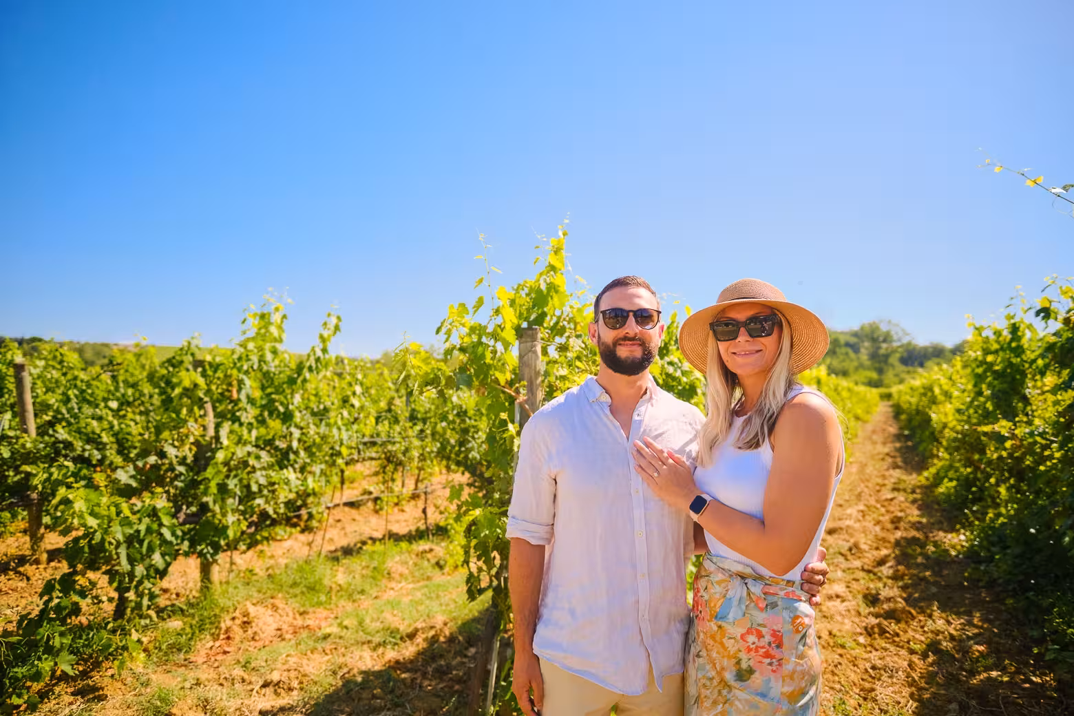 Couple enjoying a sunny day in a Chianti vineyard on a Florence to Chianti wine region tour.
