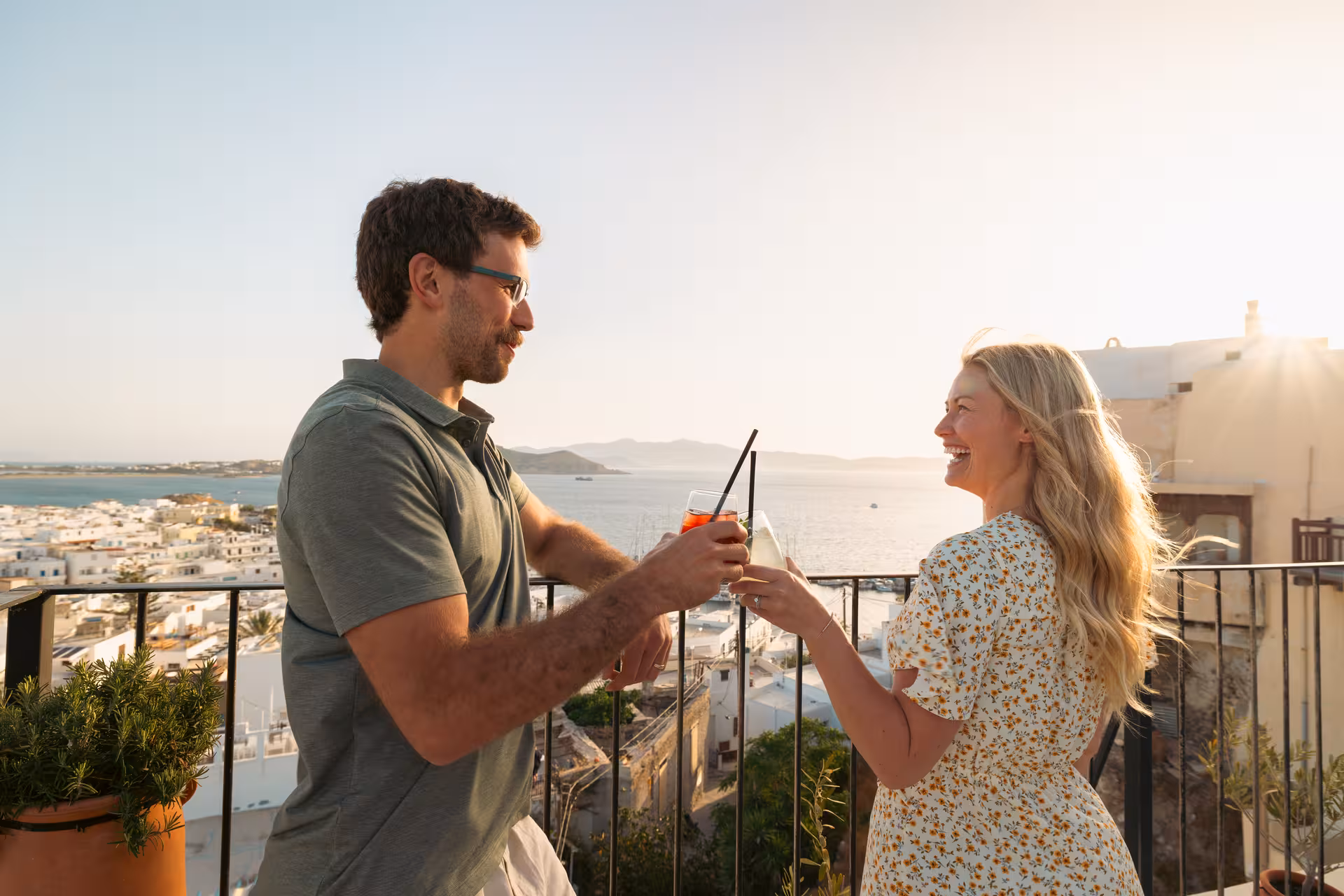 Couple toasting cocktails on a rooftop overlooking Naxos Town at sunset during the Munch Around food tour, Greece