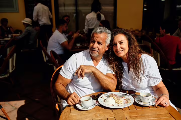A couple savoring coffee and dessert at a sunny outdoor café during a personal photography tour in Nice.