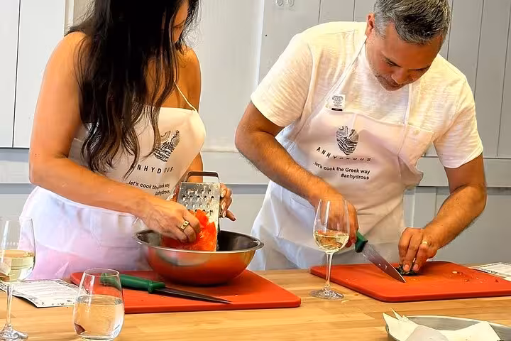 Couple grating tomato and chopping herbs in Santorini cooking class with wine tasting, 2-winery tour