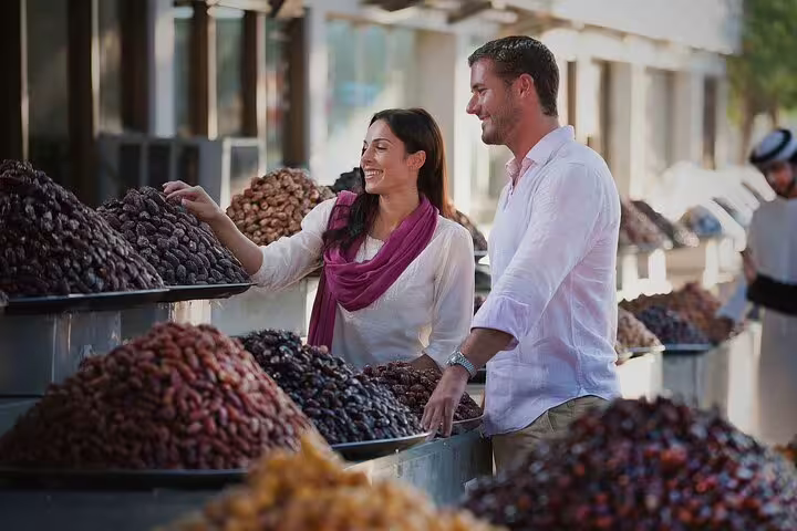 Couple explores a vibrant date market in Abu Dhabi, showcasing cultural immersion on the private 4x4 full-day tour.