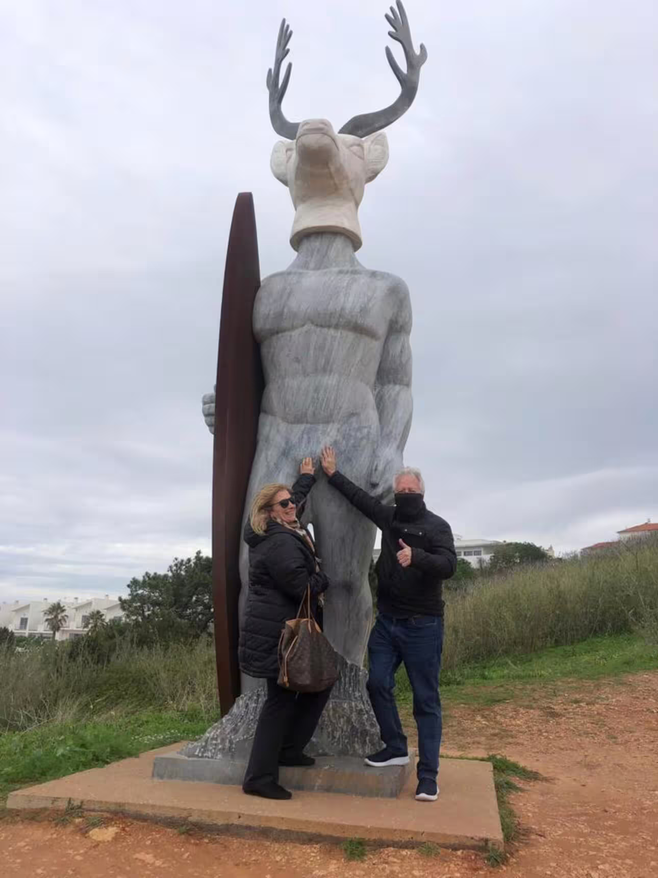 Couple posing with a unique deer statue in Nazaré during a guided tour from Lisbon.