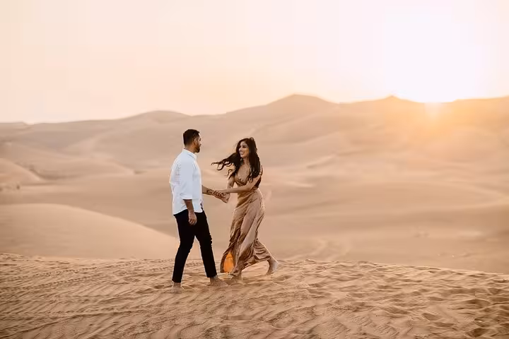 Couple walking hand in hand on golden sand dunes at sunrise during a luxury desert tour from Fes.