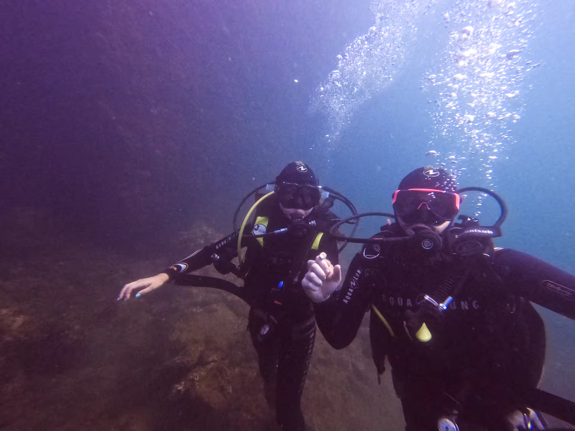 Couple of divers underwater posing for photo holding hands.