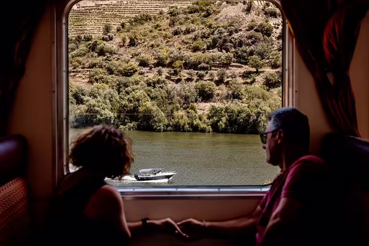Couple enjoying scenic Douro River view from train window during boat and train ride experience.