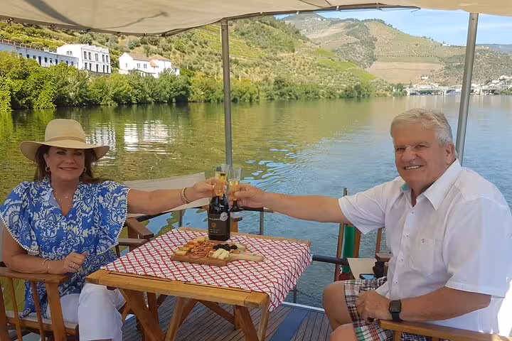 Couple toasting sparkling wine on a private Douro River boat tour with vineyard views and gourmet lunch