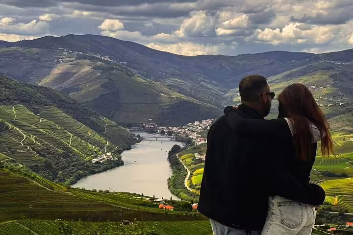 Couple embraces overlooking Douro Valley vineyards and river, highlighting romantic luxury wine tour landscapes.