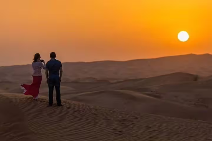Couple admiring breathtaking Dubai desert sunrise during private safari adventure.