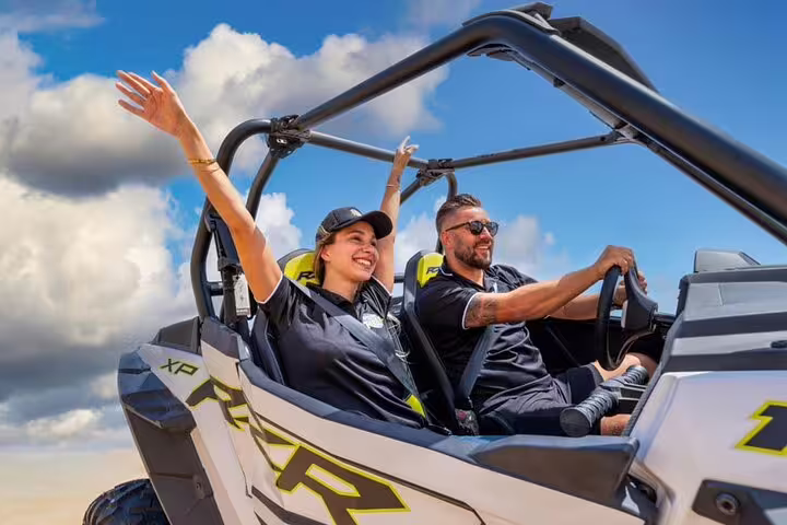 Excited couple enjoying a thrilling dune buggy ride under the clear Dubai sky, perfect for adventure seekers.