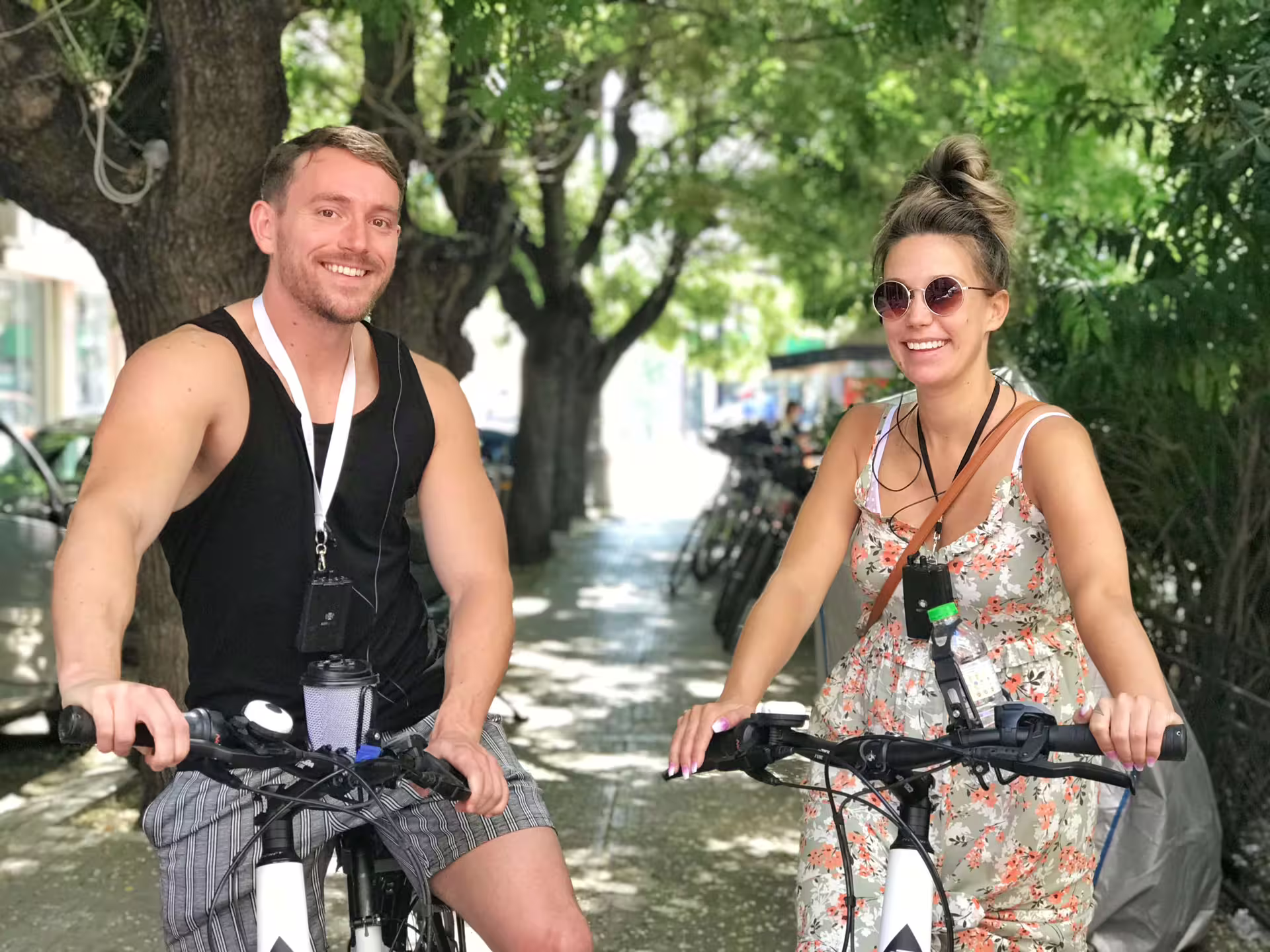 Smiling couple enjoying an e-bike tour through the scenic streets of classical Athens on a sunny day.