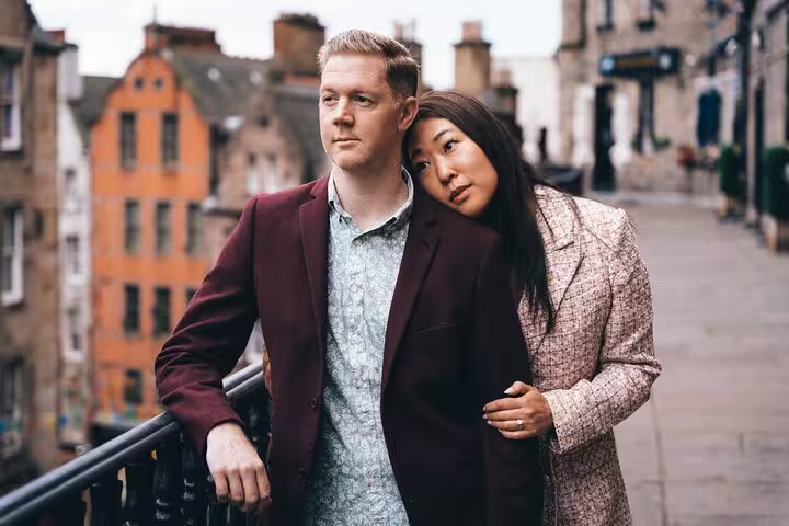 Couple shares a moment on a charming street with historic architecture in Edinburgh, perfect for a photoshoot.