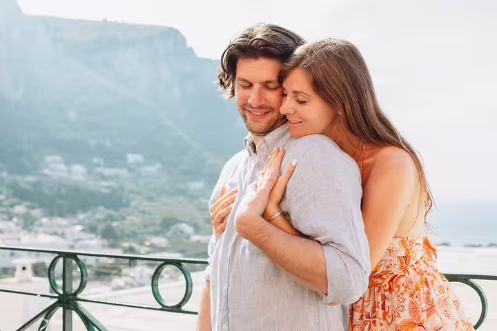Couple embracing on a scenic balcony with Naples in the background during a private photoshoot experience.