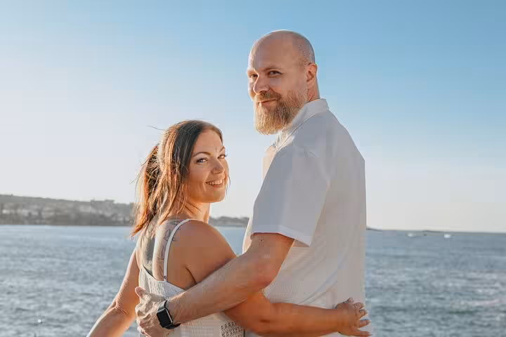 Happy couple embracing by the sea under the clear blue sky in Hersonissos, ideal for a private photo session.